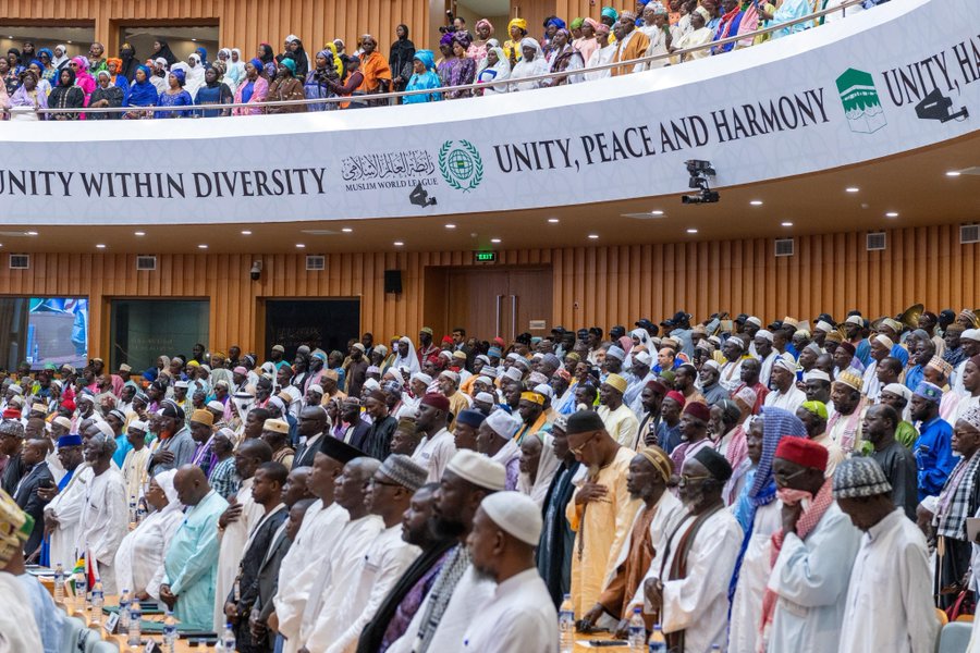 Cette photographie montre une vaste salle plénière remplie de délégués et de participants lors d'une conférence internationale organisée par la Ligue islamique mondiale.